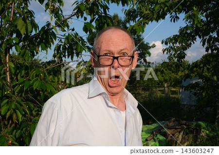 Senior man shaking head in disagreement and speaking emotionally near apple tree showing dissatisfaction and strong opinion Senior man shaking head in disagreement and speaking emotionally near apple tree showing dissatisfaction and strong opinion 143603247