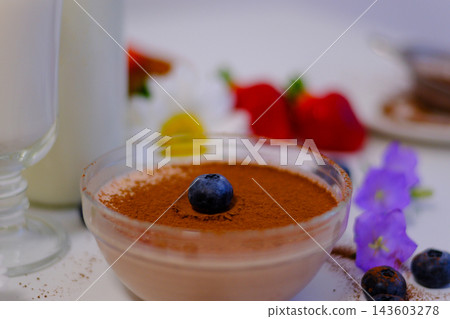 Single fresh blueberry placed on cocoa dusted chocolate dessert creating elegant finishing touch close up gourmet presentation. irresistible presentation. Single fresh blueberry placed on cocoa dusted chocolate dessert creating elegant finishing touch close up gourmet presentation. irresistible presentation. 143603278