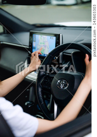 一名女子正在操作導航系統並駕駛汽車。 一名女子正在操作導航系統並駕駛汽車。 143603303