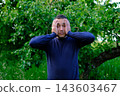 Middle aged man holding head with both hands and reacting to stress fear or unexpected situation outdoors 143603467