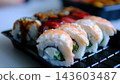 Fresh shrimp and eel sushi rolls with sesame and unagi sauce arranged in black takeaway container for Japanese food delivery 143603487