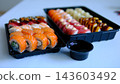 Soy sauce in plastic container near black sushi takeaway boxes delivery food close up dining scene on table  143603492