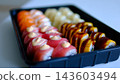 A camera smoothly moves across a sushi Sushi set with shrimp salmon tuna cream cheese sesame in black takeaway container delivery food presentation delicious Japanese cuisine prepared for takeout.  143603494