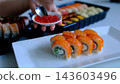 Philadelphia sushi rolls topped with red caviar using a small spoon in a fine food plating presentation 143603496