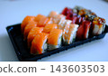 Delicious sushi delivery in black containers with assorted fresh rolls on white background 143603503