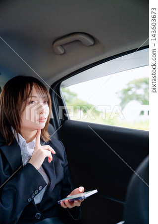 一名女子在車內看著她的智慧型手機。 143603673