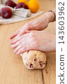 Baking process. Rolling dough. Female confectioner hand shaping sweet treat log on wooden counter preparing biscotti with red berry. 143603962