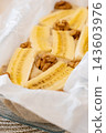 Banana bread. Fruit pastry. Sweet dough with walnut pieces in baking dish with parchment paper. Tasty homemade kitchen cake recipe. 143603976
