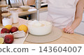 Blending food. Preparing meal. Woman chef hand mixing white cheesecake mass in bowl on kitchen countertop with modern electric equipment. 143604007