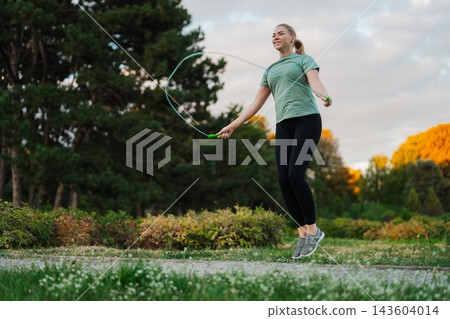 Jumping rope in a tranquil park during a sunny afternoon glow 143604014