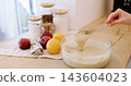 Cooking process. Pastry recipe. Woman chef hand checking thick liquid dough preparation with spoon on wooden kitchen table with fruit. 143604023
