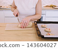 Cookies recipe. Baker work. Woman hand cut biscotti roll log dough with cranberry on home kitchen table placing treat on oven tray. 143604027