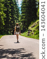 Hiker Walking Through Durmitor Forest on a Mountain Road 143604041