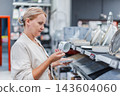 Woman Examining a Ceramic Cup in a Housewares Store 143604060