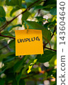 Paper note with UNPLUG message against green leafy background. Suitable for digital detox, screen-free lifestyle technology break mindfulness. 143604640