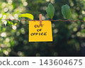 Paper note reading OUT OF OFFICE attached to leafy green plant. Suitable for digital detox, screen-free lifestyle technology 143604675