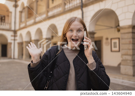 Shocked young woman talking on smartphone in European city Shocked young woman talking on smartphone in European city 143604940