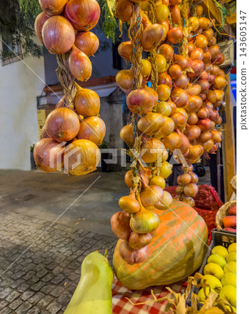 Traditional street market display with hanging onion braids and fresh pumpkins Traditional street market display with hanging onion braids and fresh pumpkins 143605147