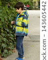 Curious young child exploring foliage in outdoor garden 143605442