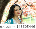 Portrait of a brunette woman on the background of pink leaves in summer, space for text 143605446