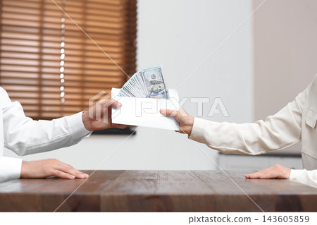 Woman giving bribe money to man at table indoors, closeup Woman giving bribe money to man at table indoors, closeup 143605859