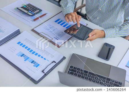 Professional financial analyst using tablet while working on analyzing charts and documents in modern office. Professional financial analyst using tablet while working on analyzing charts and documents in modern office. 143606264