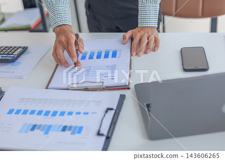 Professional financial advisor auditing company profit graph statistics paper report at desk in modern office. 143606265