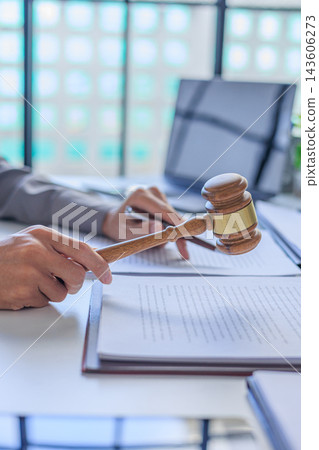 An attorney in office holding wooden gavel over legal forms during a mock trial. 143606273