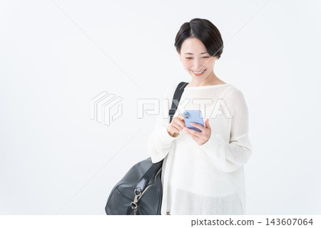 A woman going out with a large bag and her smartphone A woman going out with a large bag and her smartphone 143607064