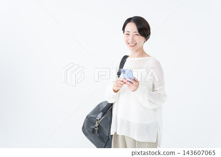 A woman going out with a large bag and her smartphone A woman going out with a large bag and her smartphone 143607065
