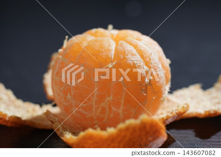 A close-up of a freshly peeled mandarin orange against a black background. A close-up of a freshly peeled mandarin orange against a black background. 143607082
