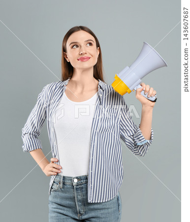 Young woman with megaphone on light grey background Young woman with megaphone on light grey background 143607687