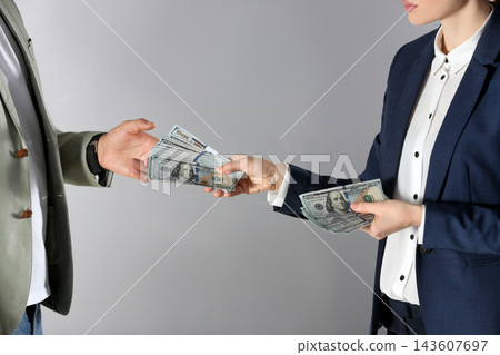 Woman giving bribe money to man on grey background, closeup Woman giving bribe money to man on grey background, closeup 143607697