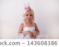 Hopeful Little Blonde Girl Holding Clasped Hands and Pleading  143608386