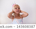 Disgusted Little Blonde Girl Wearing Princess Crown and Dress Pinching Nose  143608387