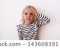 Frustrated Little Blonde Girl Holding Hand on Head and Grimacing  143608391