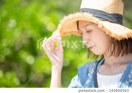 一位女模特兒側臉戴著草帽遮陽。 一位女模特兒側臉戴著草帽遮陽。 143608563