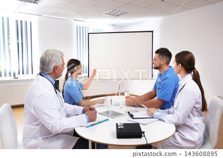 Team of doctors using video projector during conference indoors Team of doctors using video projector during conference indoors 143608895