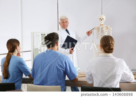 Medical students and professor studying human skeleton anatomy in classroom Medical students and professor studying human skeleton anatomy in classroom 143608898