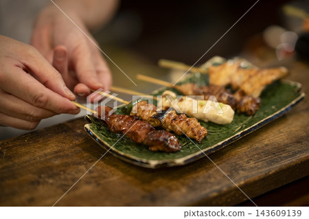 The chef's hands as he arranges the yakitori on a plate. 143609139