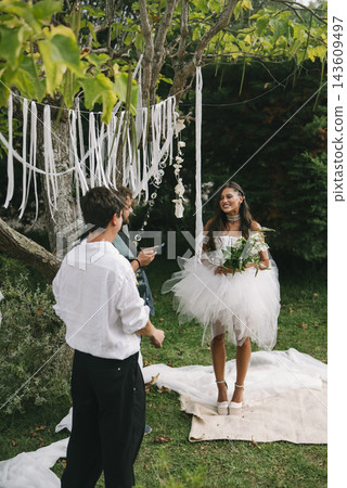 Bride Smiling Toward Groom Under White Ribbons Bride Smiling Toward Groom Under White Ribbons 143609497