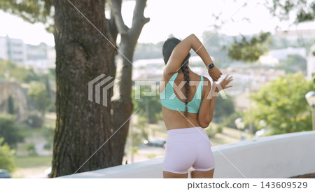 Woman Stretches Triceps Outdoors With Trees Beyond Woman Stretches Triceps Outdoors With Trees Beyond 143609529