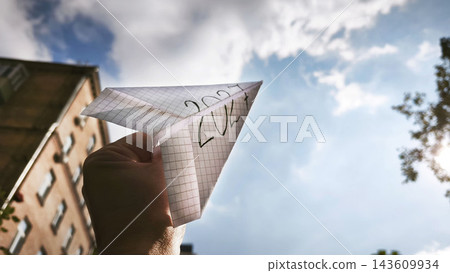 A paper airplane bearing the inscription 2027 is launched toward a bright sky, symbolizing the future, new opportunities, ambitions, innovation, dreams, and plans for the year ahead. 143609934