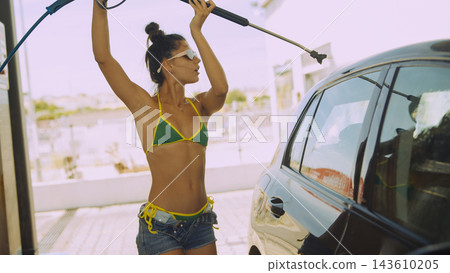 Woman washing a car with pressure hose outdoors Woman washing a car with pressure hose outdoors 143610205