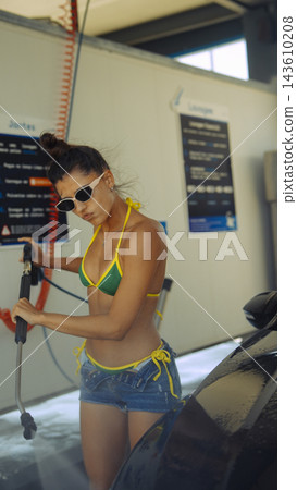 Young woman washing car at self service wash 143610208