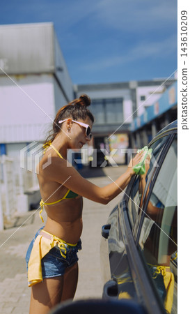 Young woman washing car outdoors on a sunny day Young woman washing car outdoors on a sunny day 143610209