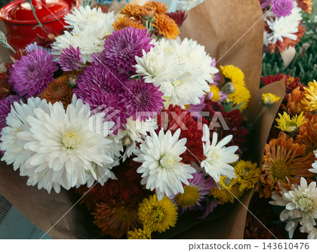 Colorful chrysanthemum flower bouquet wrapped in craft paper at market Colorful chrysanthemum flower bouquet wrapped in craft paper at market 143610476