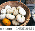 Small white and orange pumpkins in brown wicker basket at market 143610481