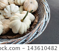 Small white decorative pumpkins in rustic wicker basket for autumn decoration 143610482