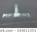 瀝青路面上畫著標示丁字路口的白色線條和裂縫。 143611353